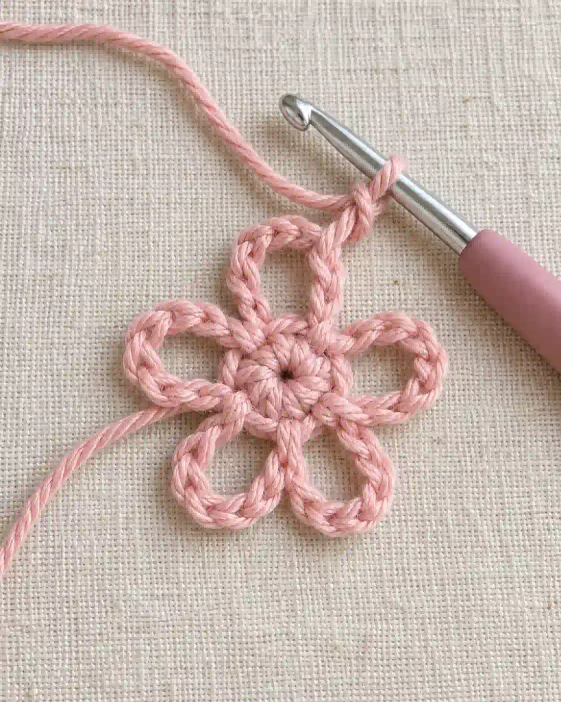 Five chain-three crochet loops arranged around a small flower center before adding petals.