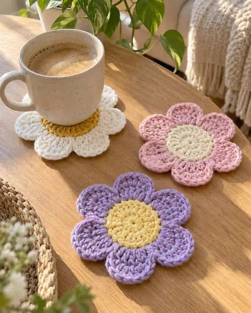 Handmade crochet flower coasters in different colors displayed with coffee mugs